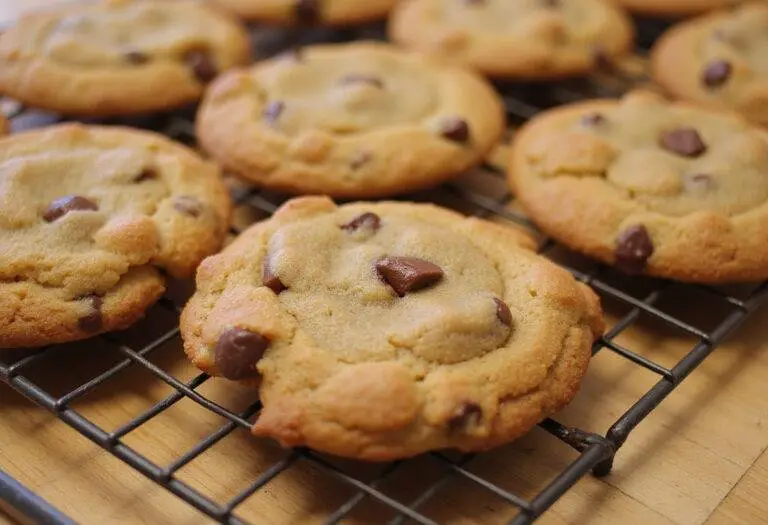 A display of freshly baked chocolate chip cookie variations on a cooling rack, highlighting unique flavors like caramel and cheesecake chocolate chip cookies.