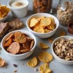 An array of high protein snacks including chips, bars, and trail mix, visually appealing and perfect for health-conscious individuals.