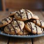 Beautifully arranged s'mores chocolate chip cookies on a plate, drizzled with chocolate and garnished with graham cracker crumbs, perfect for dessert.
