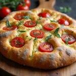 Perfectly baked sourdough focaccia bread with a crispy crust and soft inside. Showcasing the beauty of sourdough discard focaccia with vibrant toppings on a rustic cutting board.