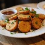 Deliciously presented Air Fryer Crispy Potatoes on a plate, garnished with herbs and accompanied by a dipping sauce, ideal for an appetizing dish.