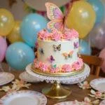 A stunning butterfly birthday cake presented on a cake stand, surrounded by festive decorations, ideal for birthdays.