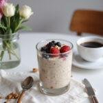 Delicious high-protein overnight oats served in a glass, decorated with berries and nuts on a stylish breakfast table for a nutritious start to the day.