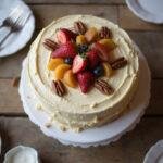Final presentation of hummingbird cake with cake mix, elegantly decorated and ready to be enjoyed with fresh fruit and pecans.