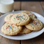 Delicious funfetti cake mix cookies with sprinkles displayed on a rustic table with a glass of milk.