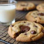 Enjoying a freshly baked small batch chocolate chip cookie, perfect for a single serving, with a glass of milk for the ultimate treat.