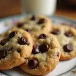 Plate of warm chocolate chip cookies without brown sugar, perfect for dessert with a glass of milk in a cozy kitchen.