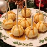Final presentation of Golden Butterbeer Swirl Cheesecake Pops on a platter with butterscotch drizzle and festive decor.