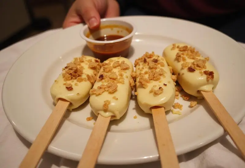 Final presentation of Hogsmeade’s Sweet Butterbeer Cheesecake Pops with a Vanilla Crunch on a decorative plate, emphasizing their delicious appearance and tempting toppings.