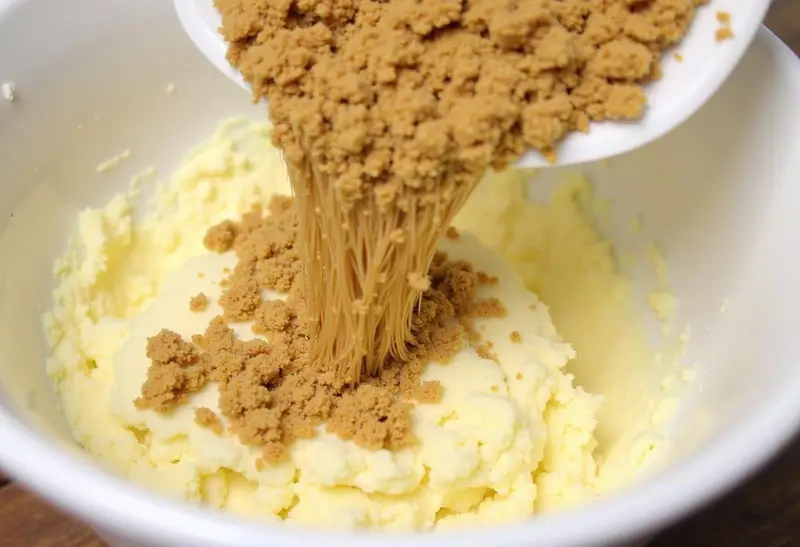 Crushed graham crackers being folded into a sweet mixture for Hufflepuff Golden Butterbeer Crunch Bars, enhancing the crunchy texture.