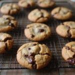 Deliciously baked Mexican chocolate chip cookies cooling on a rack with melted chocolate in a rustic kitchen environment.