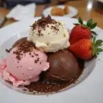 Delicious bowl of Neapolitan ice cream served with fresh fruits and chocolate shavings, perfect for a sweet treat.
