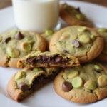 Displaying delicious homemade pistachio chocolate chip cookies on a plate with gooey chocolate and a glass of milk.