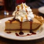 Delicious slice of Three Broomsticks Root Beer Float Pie with Butterbeer whipped cream, a perfect dessert capturing the magic of Butterbeer.