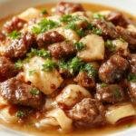 A steaming bowl of creamy beef and noodles topped with chopped parsley, showcasing tender beef strips coated in a rich, smooth sauce and al dente noodles, garnished with a sprinkle of herbs on a rustic wooden table.