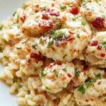 A plate of creamy smothered chicken served over fluffy rice, garnished with herbs and a rich gravy coating the tender chicken pieces.