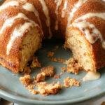 A beautifully decorated bundt cake with intricate icing designs and fresh fruit garnishes, displayed on an elegant cake stand.