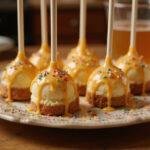 Deliciously finished Harry Potter Butterbeer Cheesecake Pops with Golden Butterscotch Drizzle beautifully arranged on a plate.