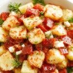 A vibrant bowl of Healthy Greek Potato Salad with diced potatoes, cherry tomatoes, cucumbers, red onions, and fresh herbs topped with feta cheese