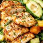 A vibrant Mediterranean chicken bowl featuring grilled chicken slices, colorful vegetables, hummus, and fresh herbs arranged beautifully in a bowl.