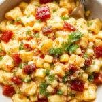 Colorful bowl of Healthy Street Corn Pasta Salad with vibrant corn, pasta, fresh herbs, and crumbled cheese garnished with lime wedges.