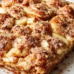A delicious heartwarming apple cinnamon sheet cake on a platter, topped with cinnamon sugar and fresh apple slices, ready to serve.