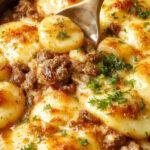 A hearty Hobo Casserole with layers of seasoned ground beef, sliced potatoes, and melted cheese in a rustic baking dish.