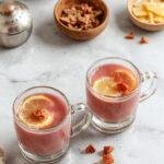 A vibrant cup of Kashmiri Pink Chai with frothy pink tea, garnished with crushed pistachios and served in an elegant glass cup.