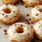 Golden-brown Korean Milk Cream Donuts arranged elegantly on a white plate, showcasing their soft, fluffy texture and glossy exterior. The donuts are topped with a subtle dusting of powdered sugar and garnished with delicate sprigs of fresh mint, creating an inviting and visually appealing presentation.