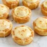 A close-up of a magical mini lemon impossible pie on a decorative plate, showcasing its golden crust and vibrant lemon filling topped with mint leaves.