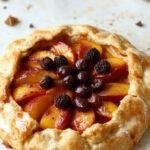 A freshly baked peach galette with golden crust, filled with sliced peaches and drizzled with honey, served on a rustic wooden table.