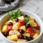 A vibrant summer fruit salad featuring colorful slices of watermelon, kiwi, strawberries, blueberries, and orange segments arranged in a clear glass bowl, garnished with fresh mint leaves, with a bright and inviting background.