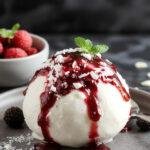 A vibrant bowl featuring a creamy yogurt bomb topped with fresh mixed berries and drizzled berry sauce, perfect for summer dessert.