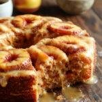 A slice of Simply Incredible Brown Sugar Peach Cake showcasing layers of moist peach and brown sugar sponge topped with caramelized peaches and whipped cream.