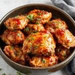 A close-up of a juicy, golden-brown smoked paprika chicken breast with smoky red and orange hues, garnished with fresh herbs on a rustic platter, textures crisp on the outside and tender inside