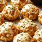 A plate of Sweet & Spicy Hot Honey Chicken Biscuits featuring golden-brown biscuits topped with crispy chicken pieces drizzled with hot honey glaze, garnished with sesame seeds and fresh herbs.