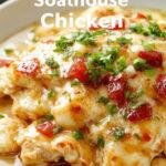 A plate of juicy, golden-brown smothered chicken topped with melted cheese and sautéed onions, garnished with fresh herbs, served alongside mashed potatoes and vibrant vegetables. The dish is plated on a rustic white dish with a fork and knife beside it, highlighting its hearty and comforting appeal.