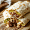 A close-up of Big Mac Wraps sliced to reveal juicy beef, melted cheese, crisp lettuce, dill pickles, and sesame Big Mac sauce roped in a soft tortilla on a light wooden board, with natural daylight and subtle steam.