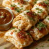 Golden crispy chicken rolls filled with melted mozzarella and spinach, sliced to show gooey cheese, arranged on a white plate with a light drizzle of olive oil and a sprinkle of paprika and parsley; a rustic wooden board and a small bowl of dipping sauce set the scene