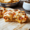 A golden-brown crispy pizza grilled cheese cut in half on a light wooden board, mozzarella melted, marinara swirls, pepperoni and basil accents, sunshine lighting, casual home-kitchen styling.