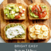 Four open-faced toast slices arranged on a light wood board. One features avocado lemon mash, another is tomato and feta, a third is hummus with cucumber slices, and the fourth is ricotta with banana drizzle. Fresh herbs, olive oil drizzle, sea salt, and cracked pepper add color and texture to a bright, healthy breakfast display.
